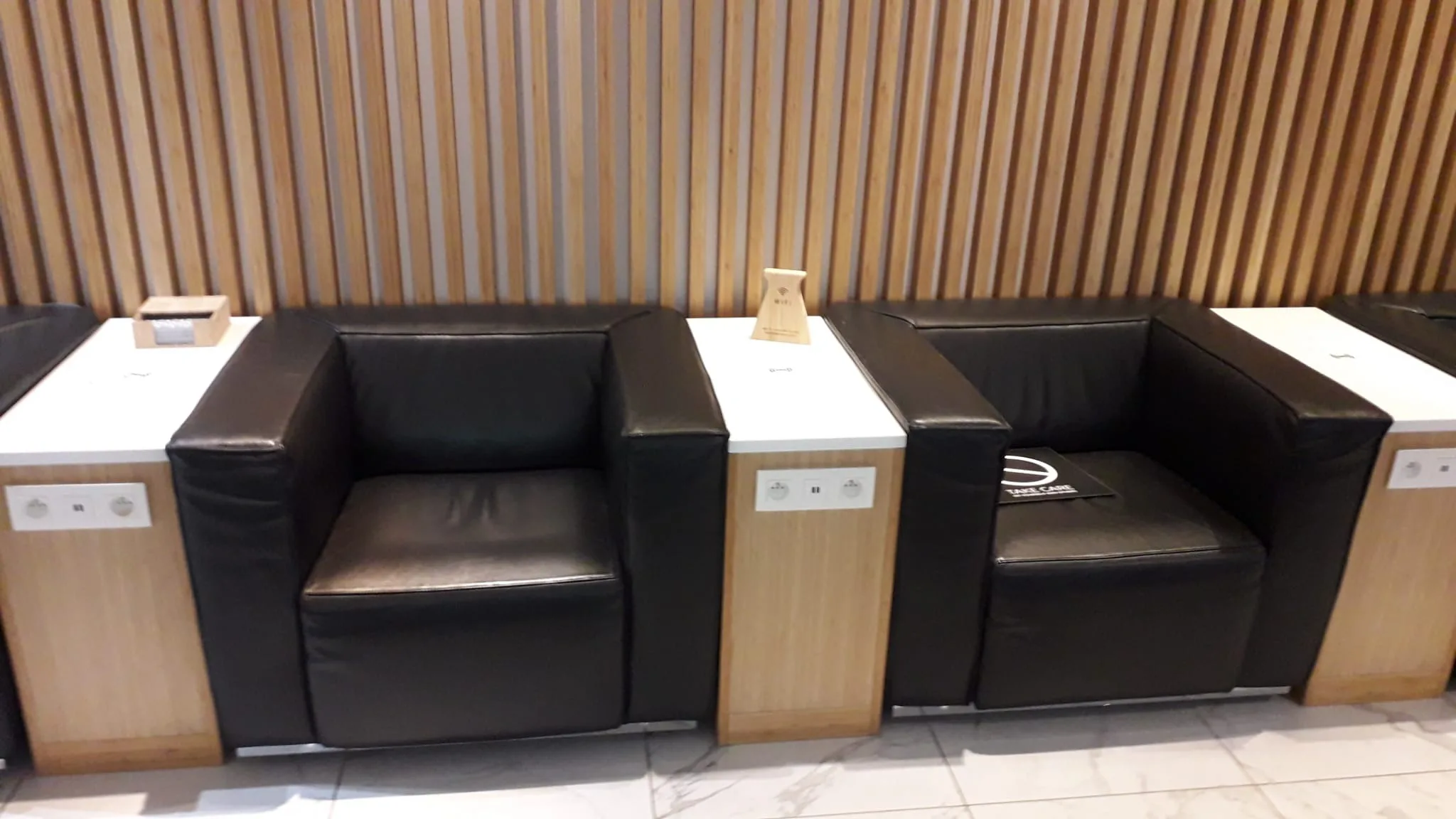 Schwarze Lederstühle vor Holzwänden im Loungebereich