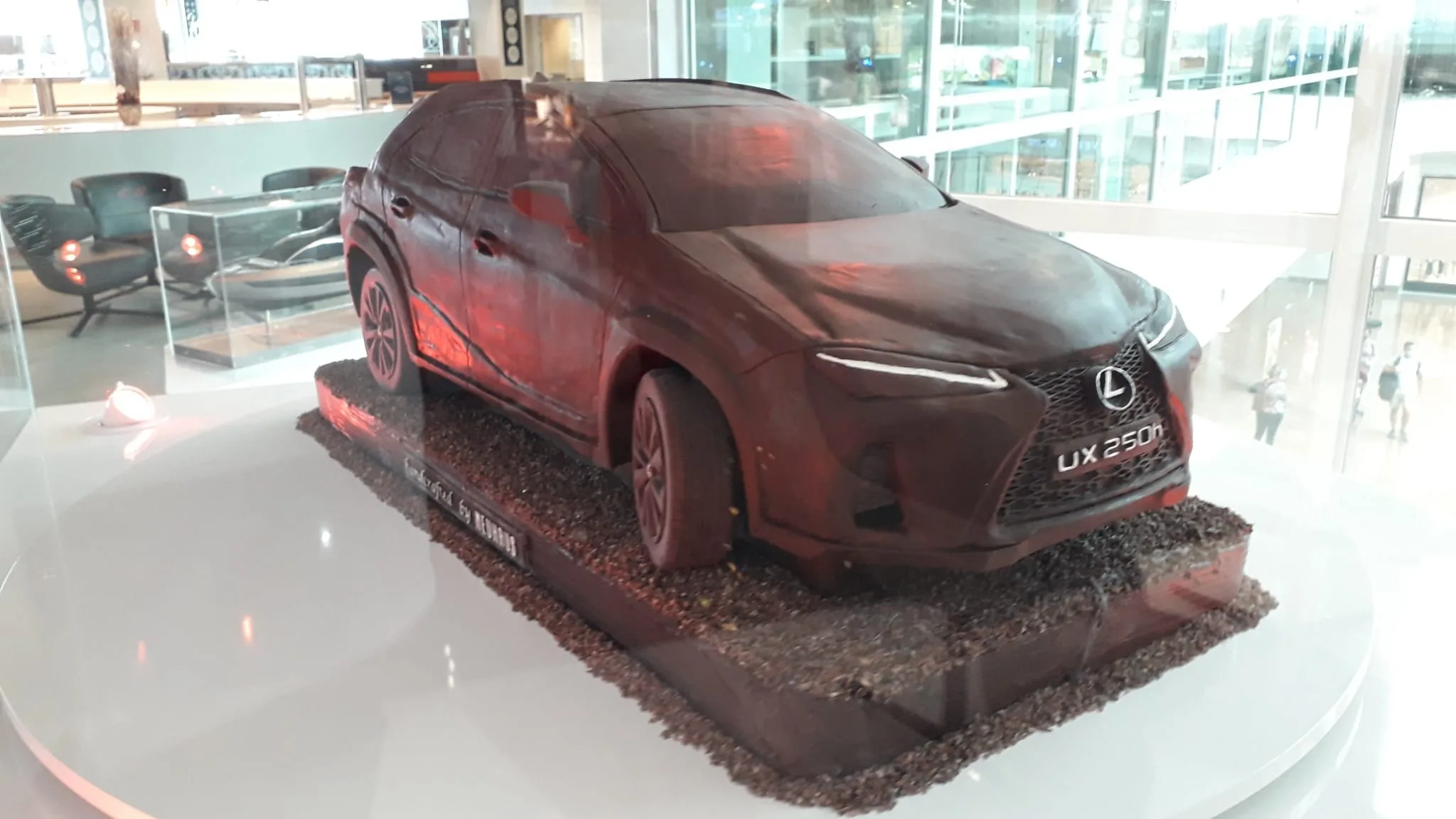 Lexus UX 250h Modell aus Schokolade auf Podest im Flughafenlounge