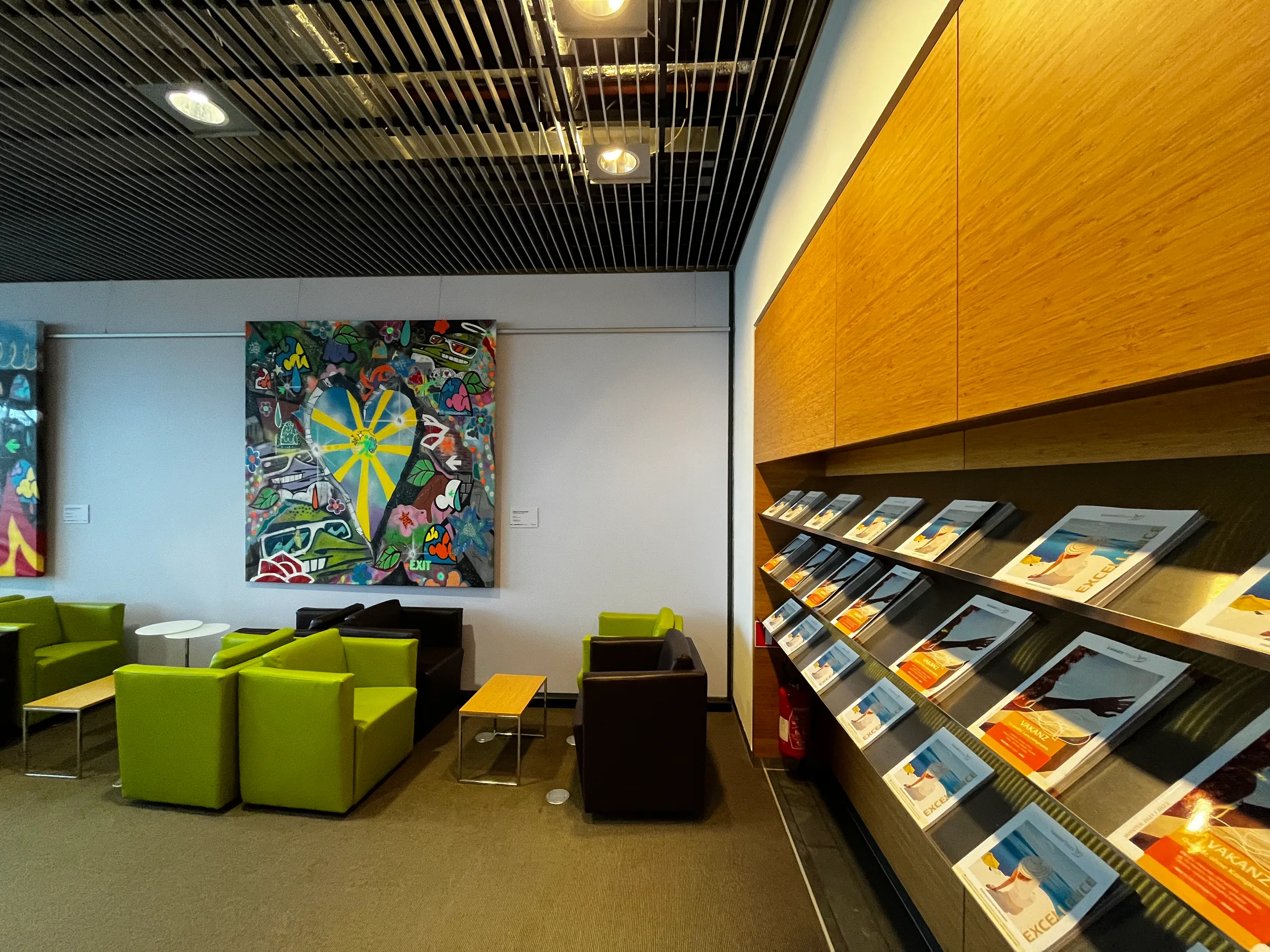 Lounge mit buntem Gemälde und grünen Sesseln