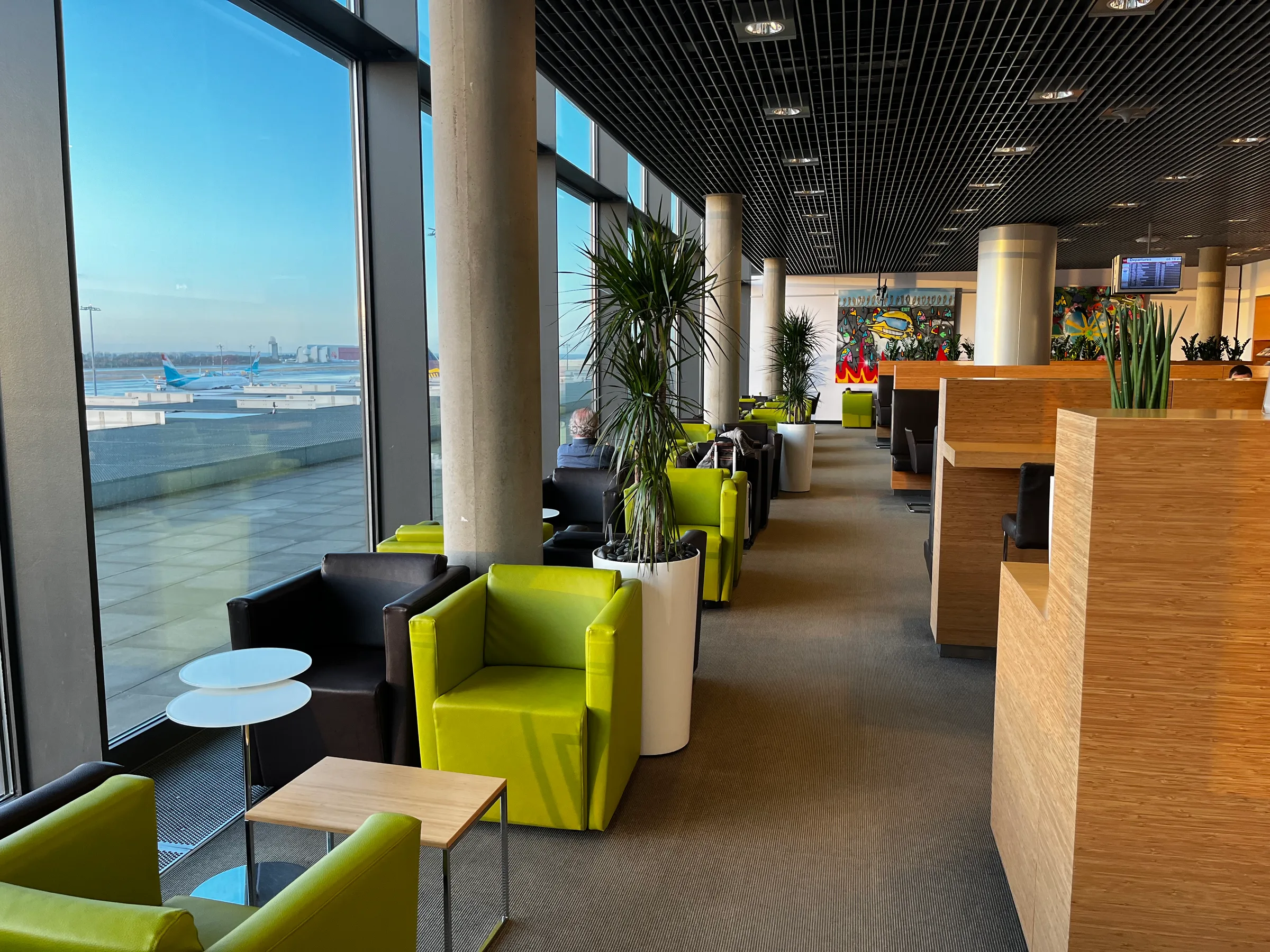 Lounge mit Sesseln und Pflanzen am Flughafenfenster