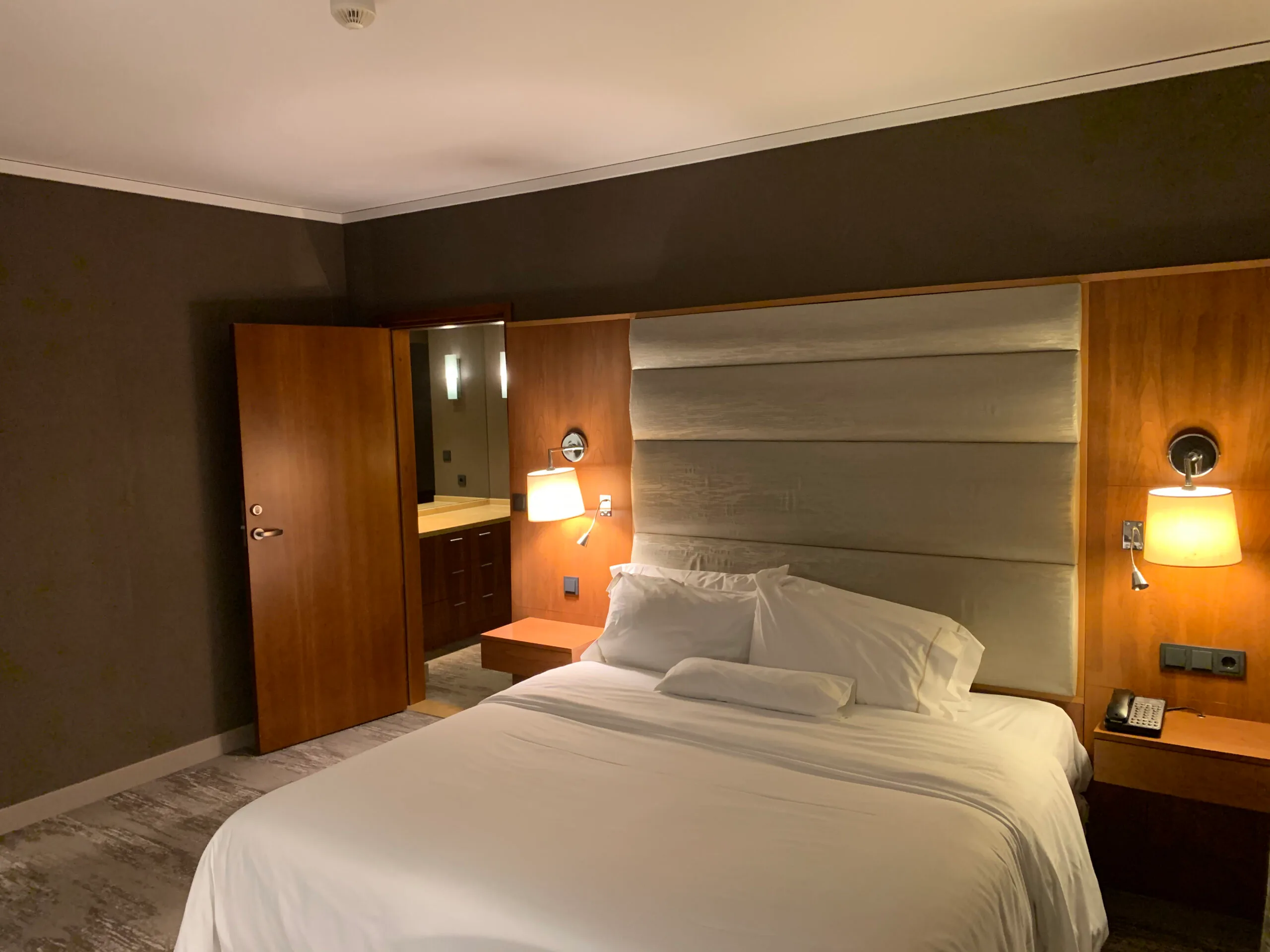 Hotelzimmer mit Doppelbett und Nachttischlampen in Grautönen