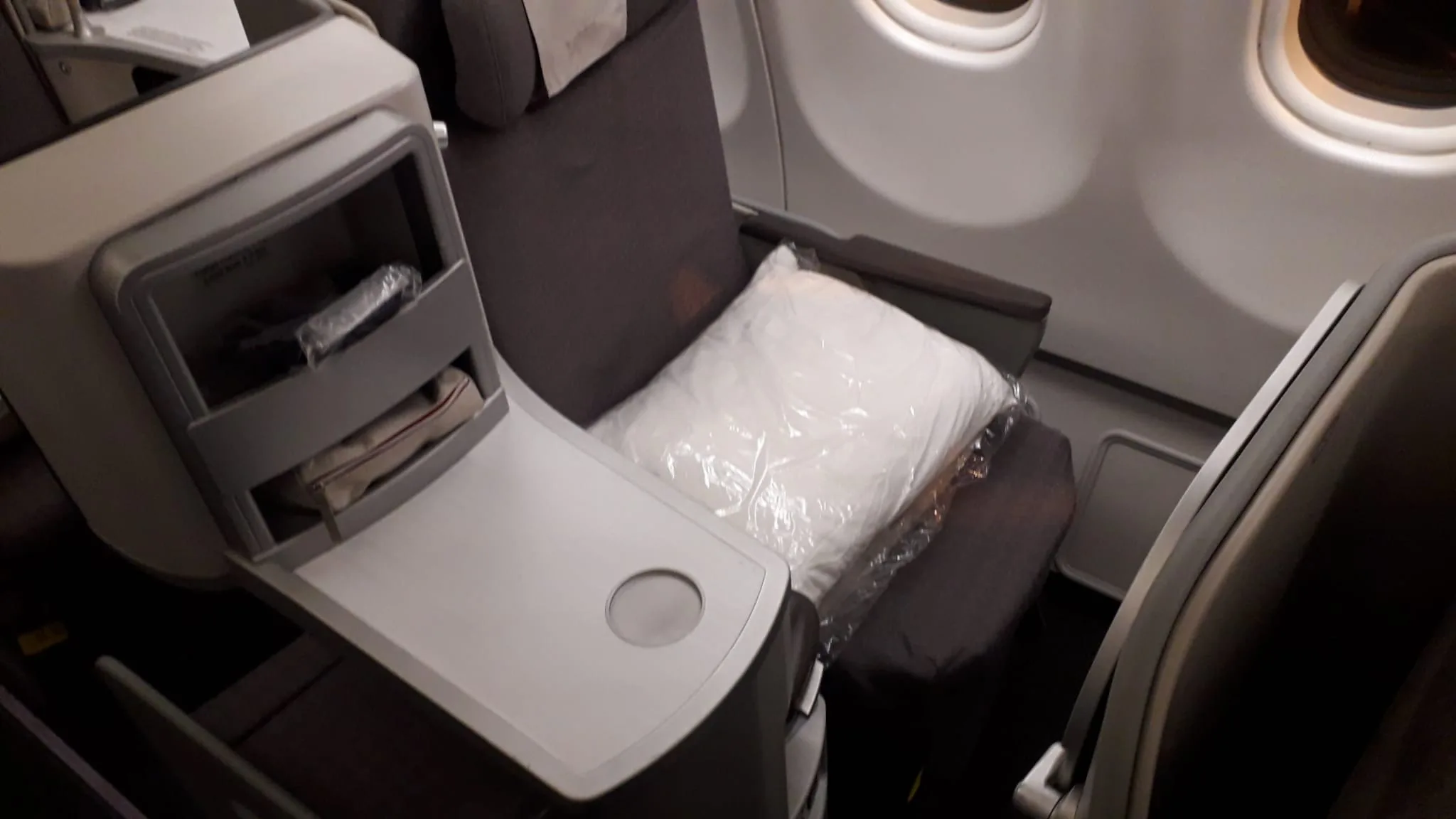 Business Class Sitz mit Kopfkissen und Tisch im Flugzeug
