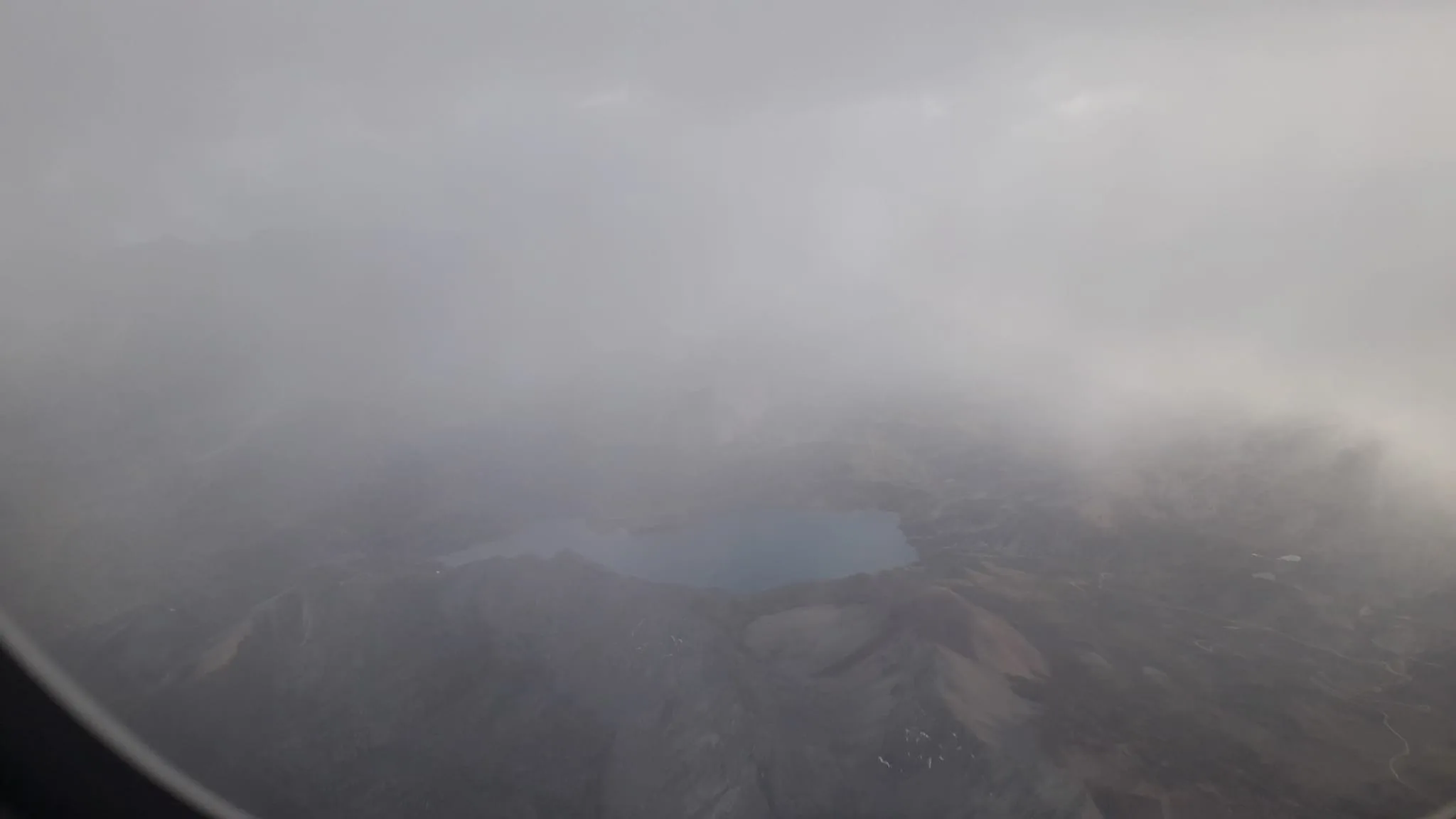 Luftaufnahme von Berglandschaft mit See durch Wolken