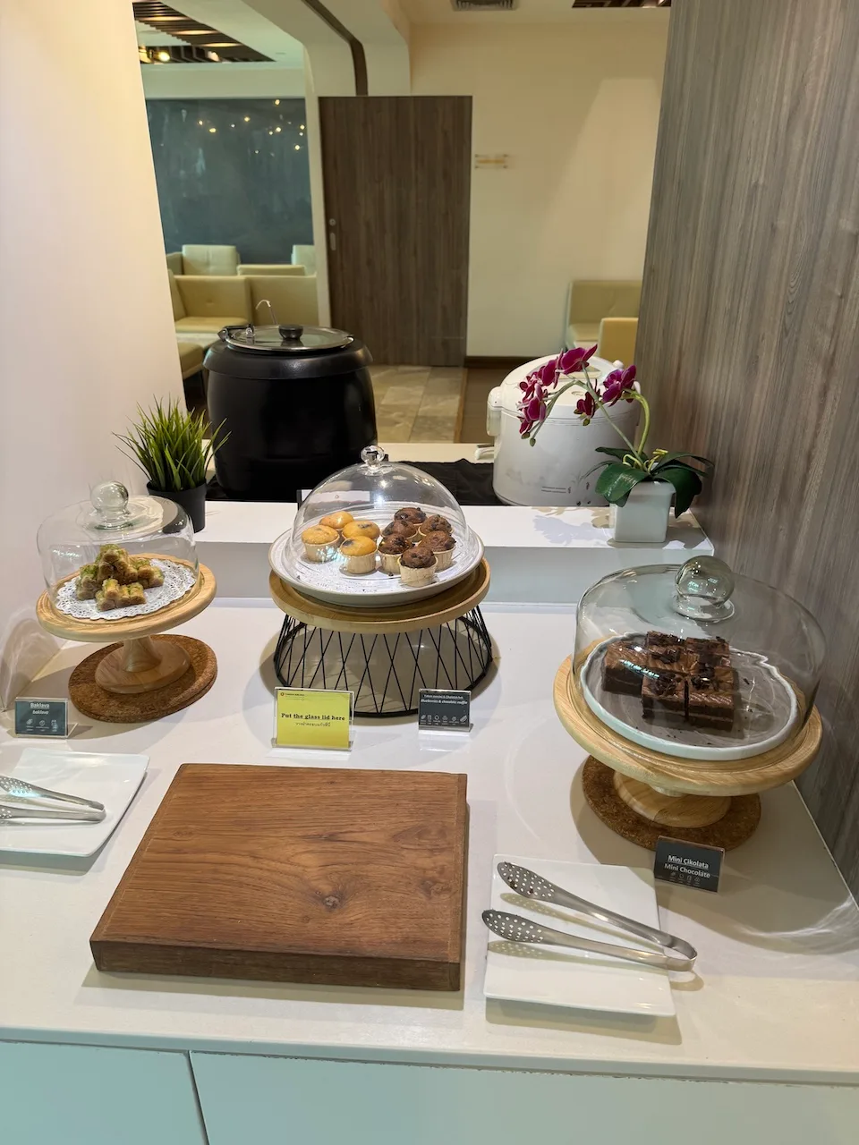 Buffet mit verschiedenen Gebäcksorten und Schokoladenkuchen unter Glasbehältern