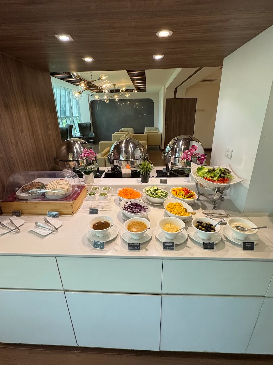 Buffet mit Salat und verschiedenen Beilagen auf einem weißen Tresen