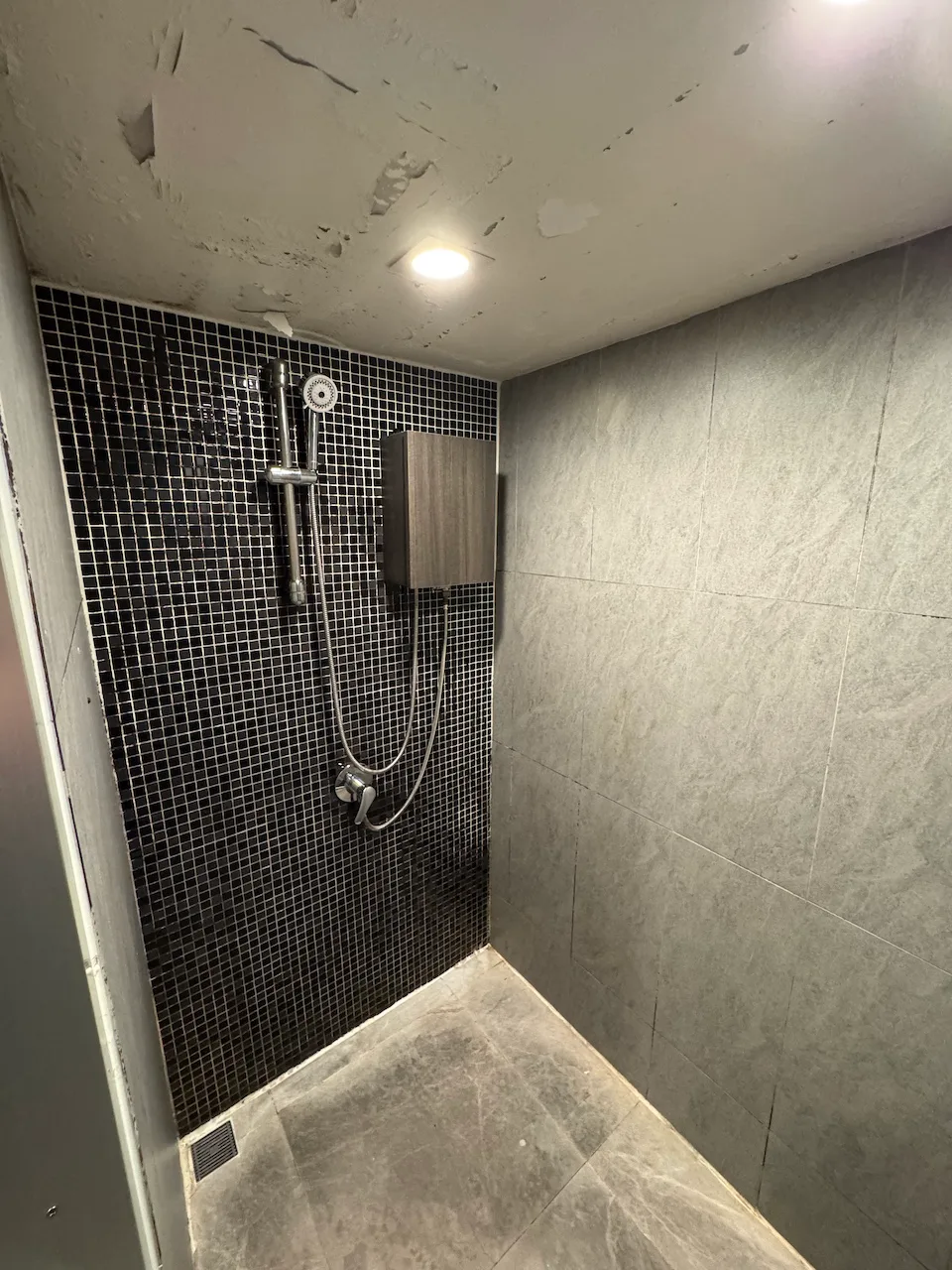 Duschbereich mit Mosaikwand und Handbrause