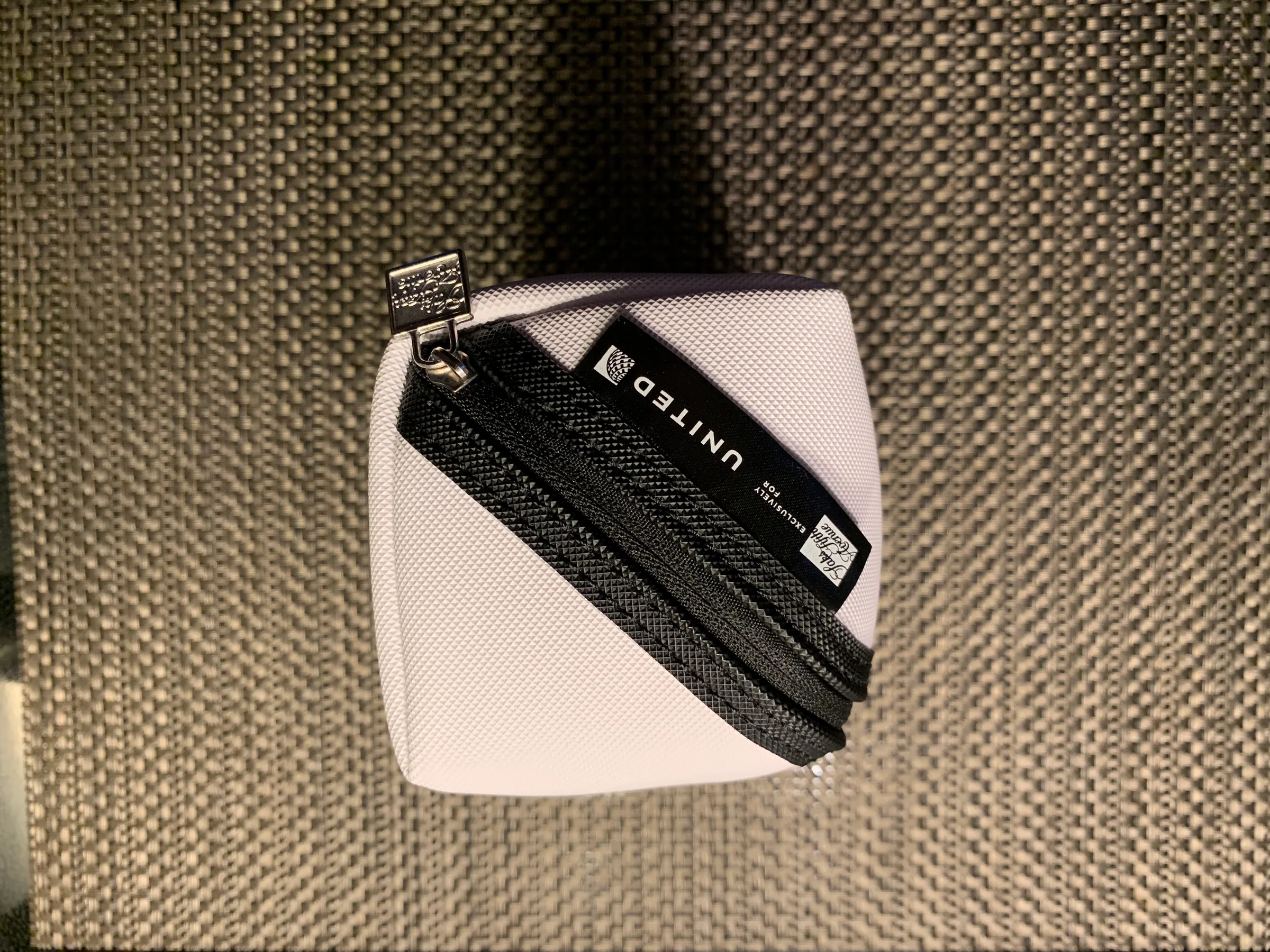 Weißer Taschenbeutel mit schwarzer Reißverschlussleiste und Etikett