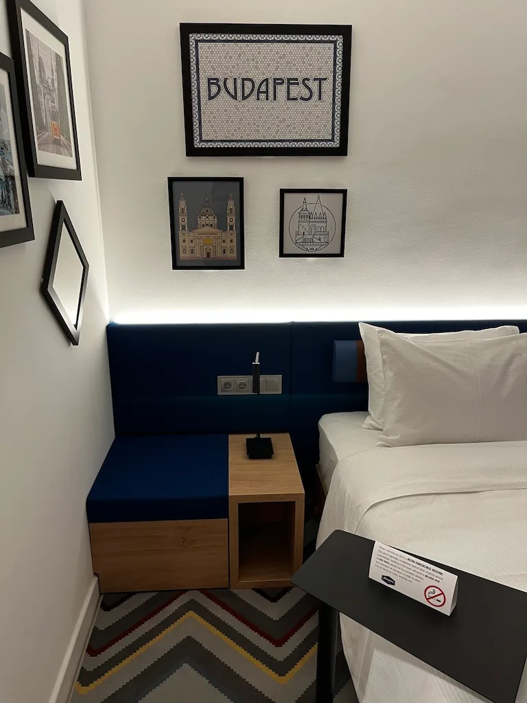 Hotelzimmer mit Doppelbett und Wandbildern von Budapester Sehenswürdigkeiten