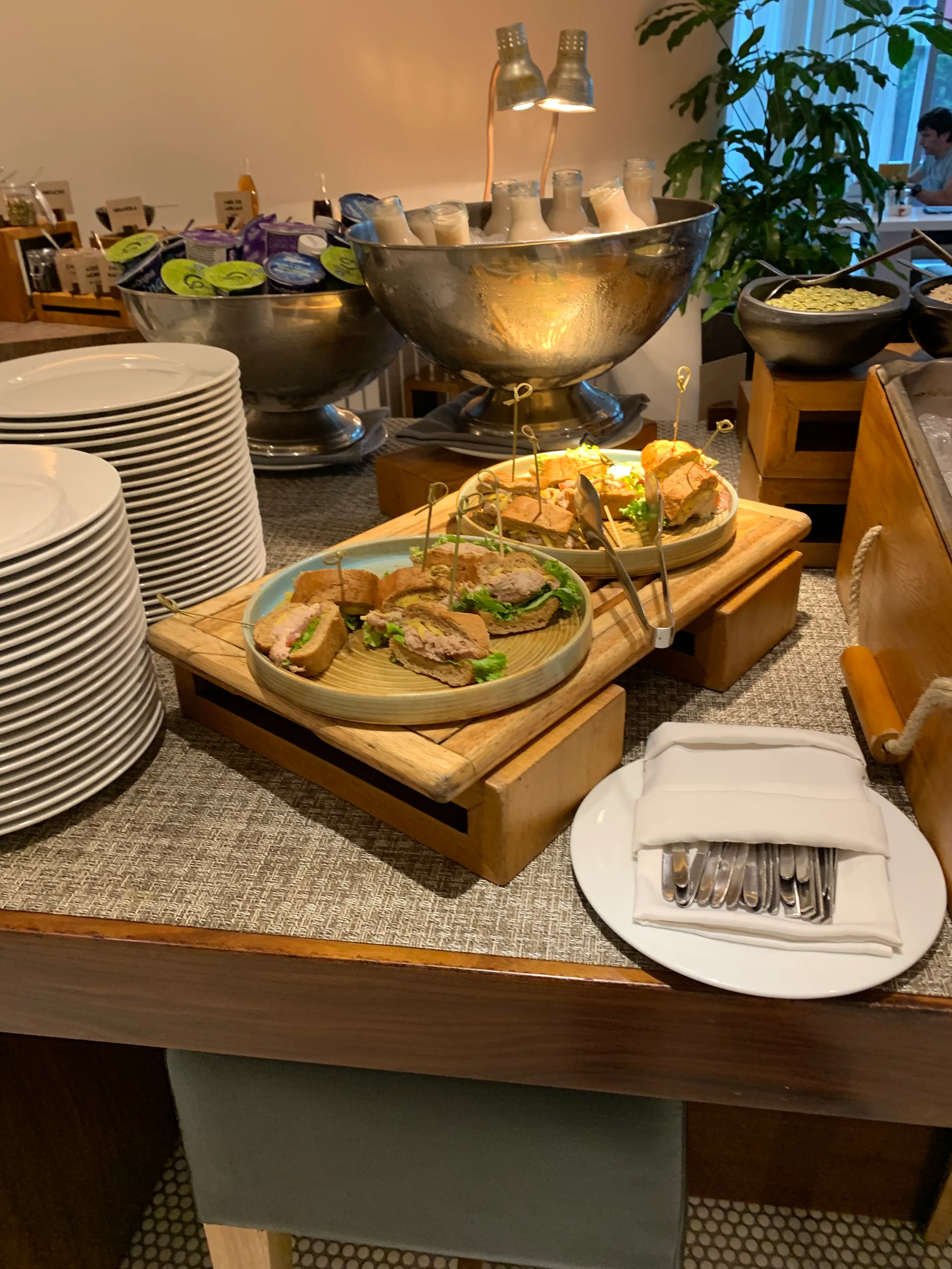 Buffet mit Sandwiches auf Holzbrettern und Geschirr im Hintergrund