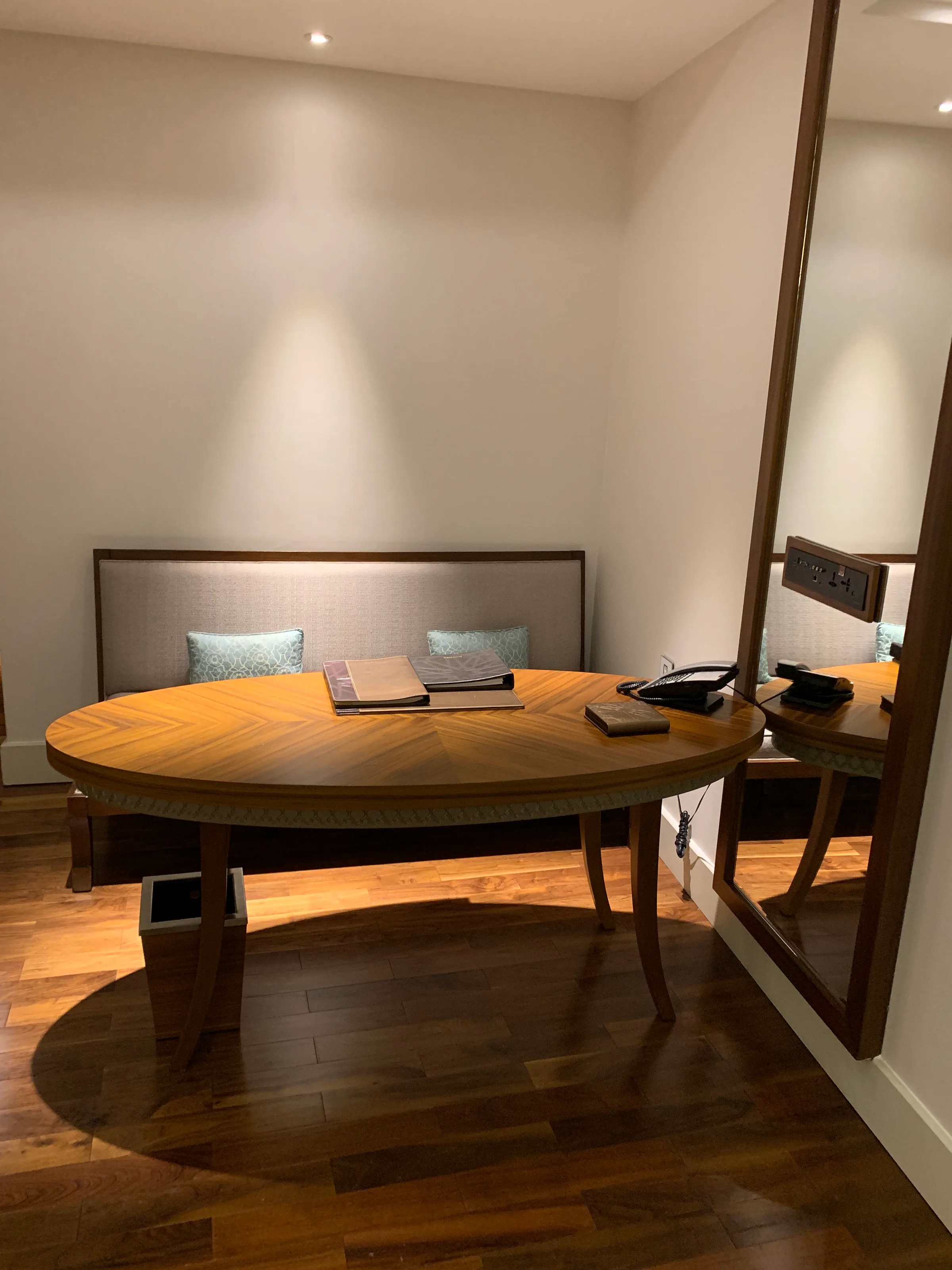 Hotelzimmer mit ovaler Holztisch und Kopfteil im Hintergrund