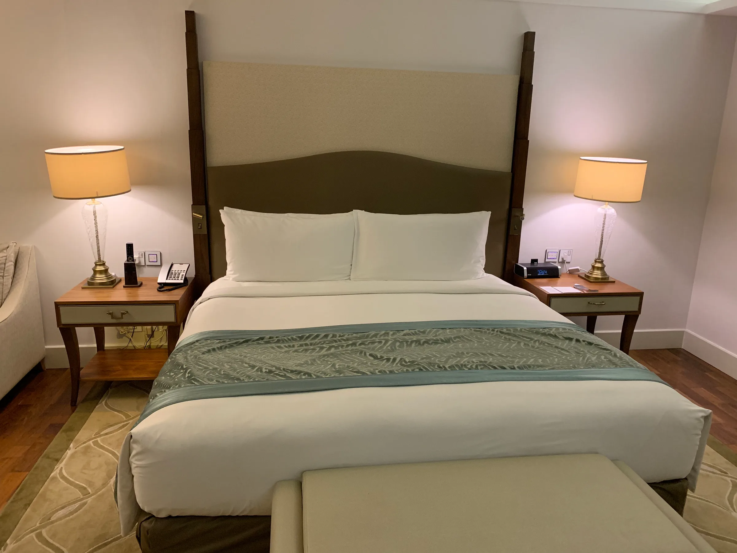 Doppelbett im Hotelzimmer mit grauem Kopfteil und Nachttischen
