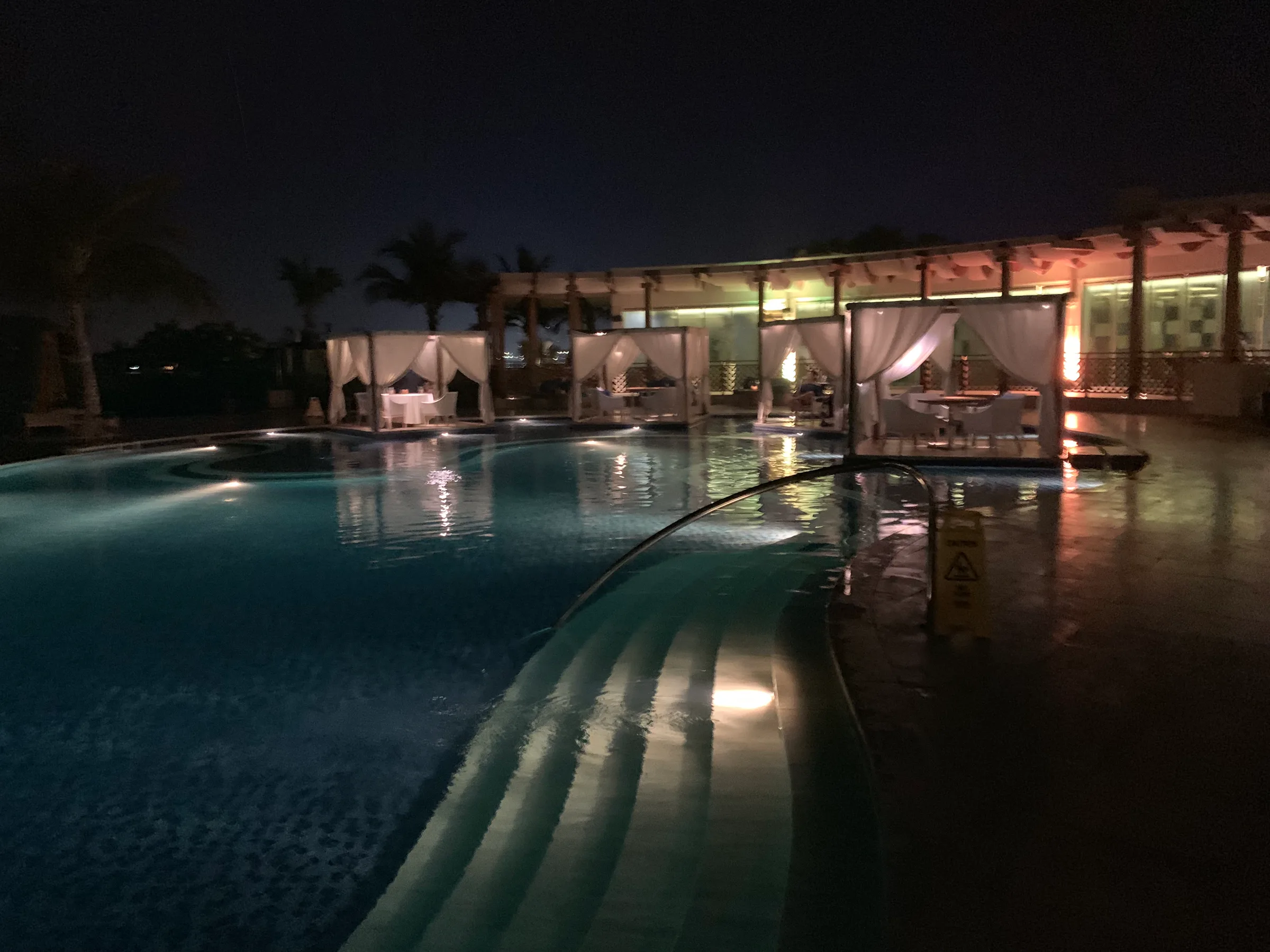 Nachtansicht des Poolbereichs im Waldorf Astoria Dubai Palm Jumeirah mit beleuchteter Terrasse