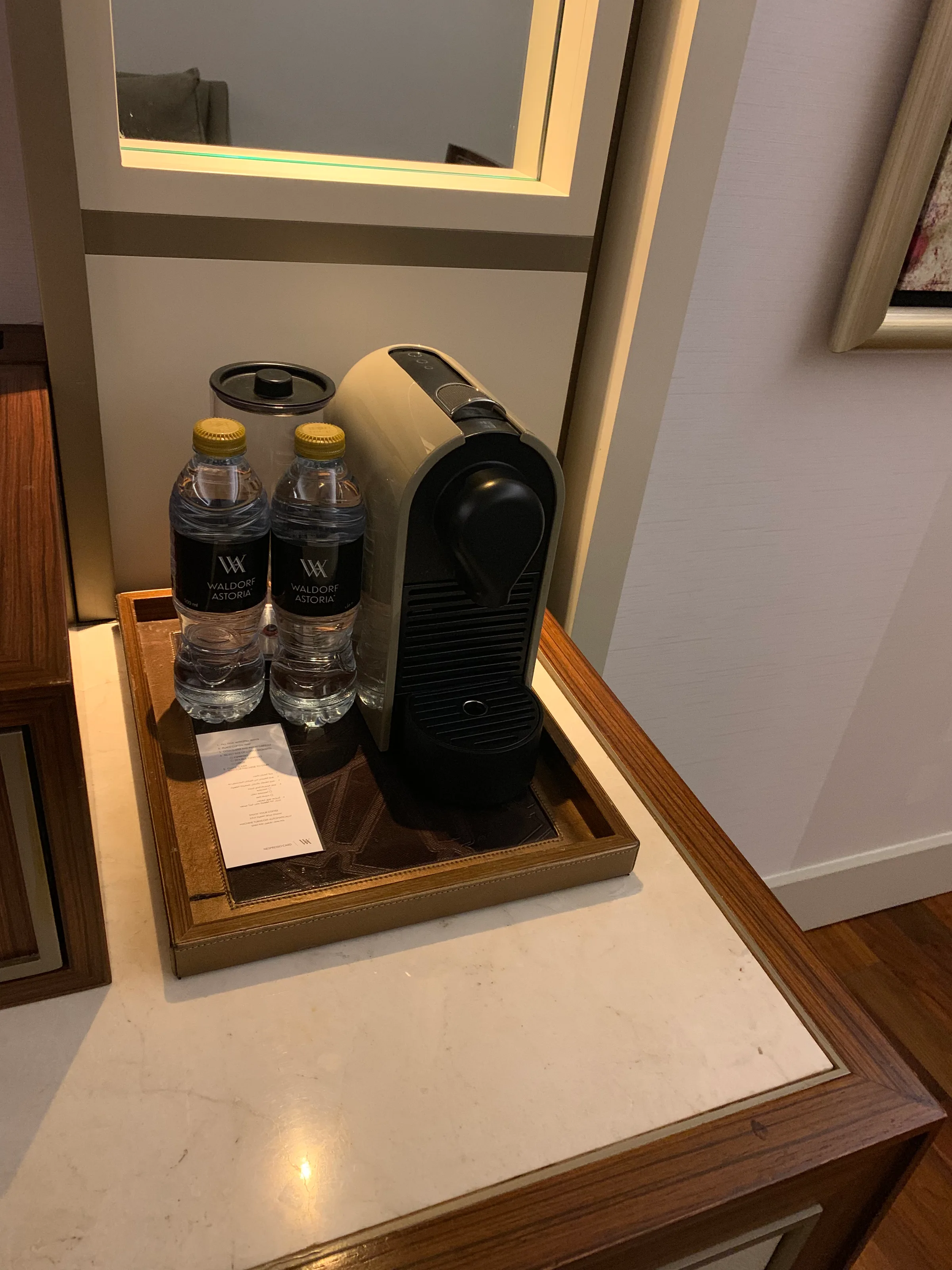 Wasserflaschen und Kaffeemaschine auf Tablett im Zimmer