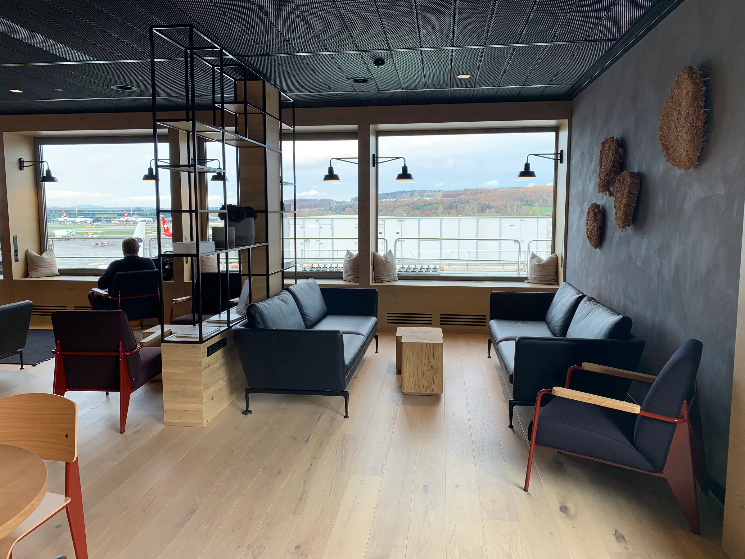 Lounge mit Sesseln und Couchen mit Blick auf Flughafen und Landschaft